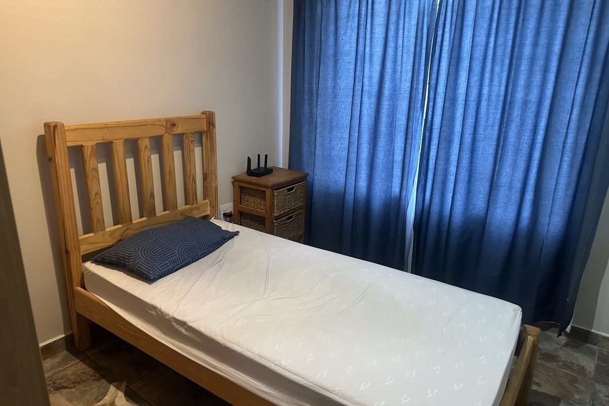 A functional bedroom featuring tiled flooring and full-length curtains, providing a simple and practical living space.
