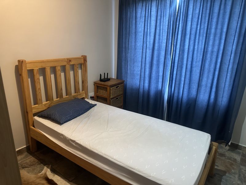A functional bedroom featuring tiled flooring and full-length curtains, providing a simple and practical living space.
