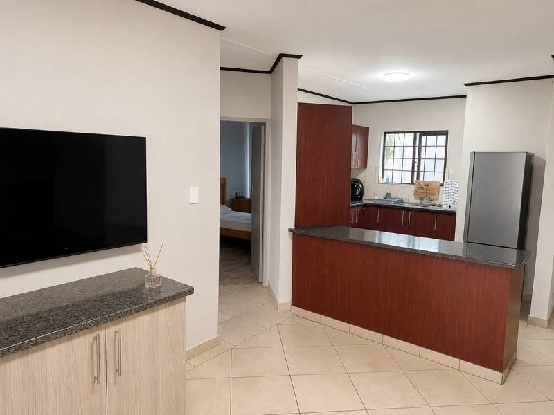 Open plan living area featuring a kitchen with dark wood cabinetry, granite countertops, breakfast bar, and tiled flooring throughout.