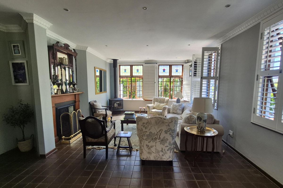 Spacious living room featuring a fireplace, wood-burning stove, stained glass windows, plantation shutters, and classic crown molding with tiled flooring.