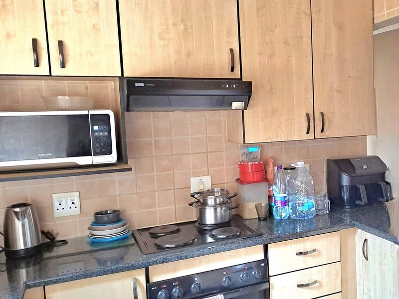 A functional kitchen featuring light wood cabinetry, dark granite countertops, a built-in oven, electric hob, and an extractor fan.