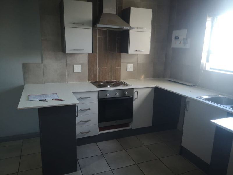 Modern kitchen featuring built-in cabinetry, stone countertops, integrated oven, electric hob, and stainless steel extractor fan with tiled splashback.