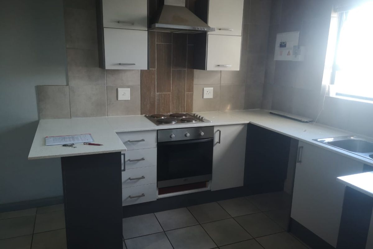 Modern kitchen featuring built-in cabinetry, stone countertops, integrated oven, electric hob, and stainless steel extractor fan with tiled splashback.