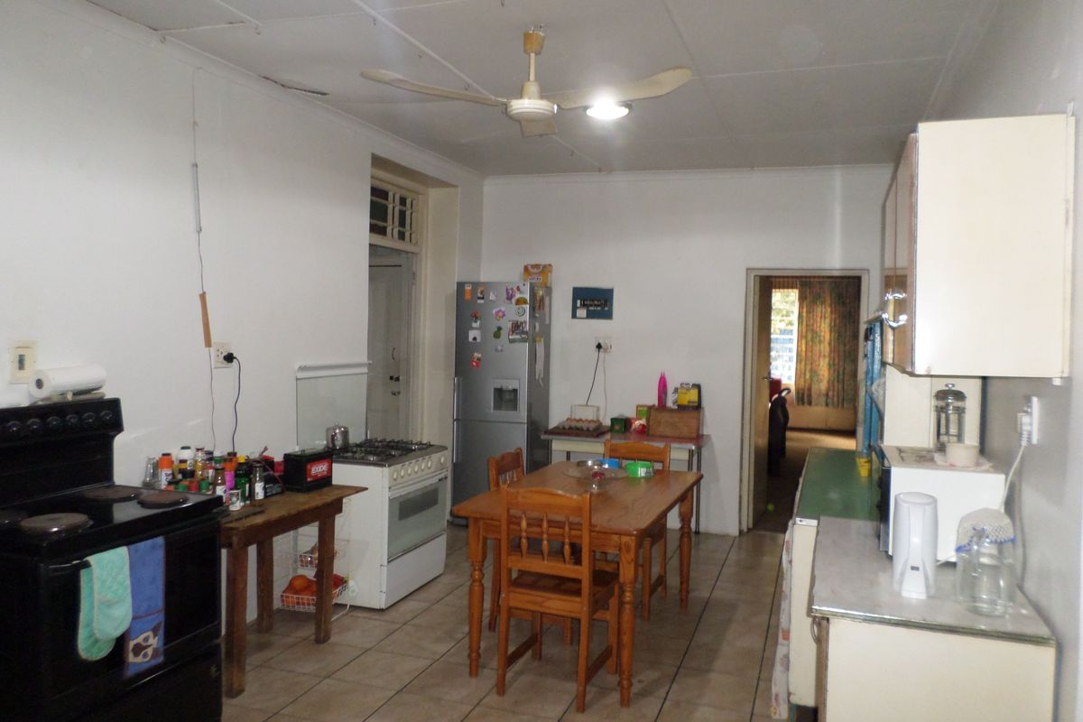 A functional kitchen area featuring tiled flooring, dual stove units, and built-in cabinetry, requiring some cosmetic updates to the ceiling and finishes.