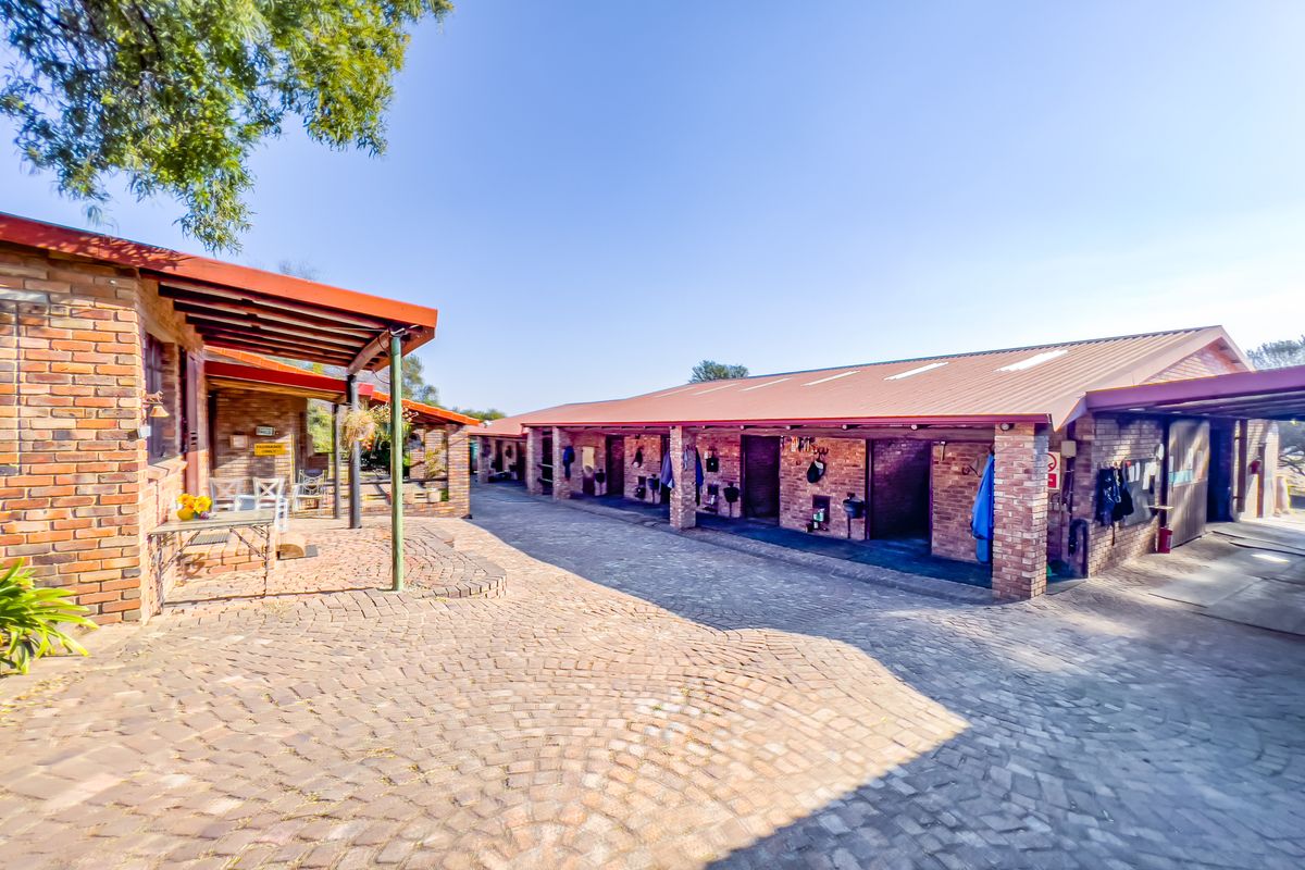 A well-maintained stable block featuring exposed brickwork, a paved courtyard, and covered walkways, suitable for equestrian use on a small holding.