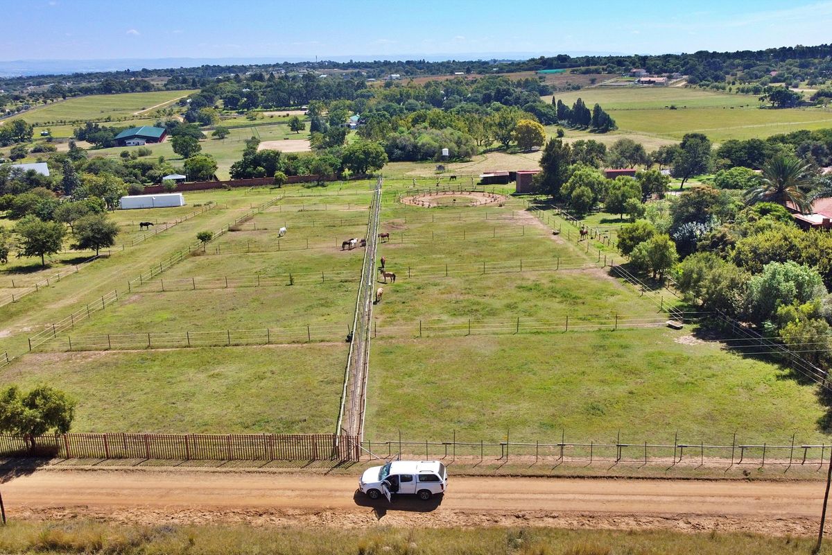 Aerial view of a small holding property featuring extensive fenced paddocks, grazing land, and established trees in a rural setting.
