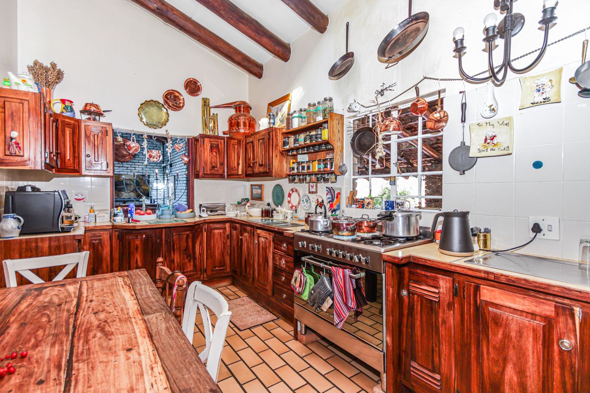Rustic country-style kitchen featuring solid wood cabinetry, exposed timber ceiling beams, a gas stove, and tiled flooring with a warm, traditional aesthetic.