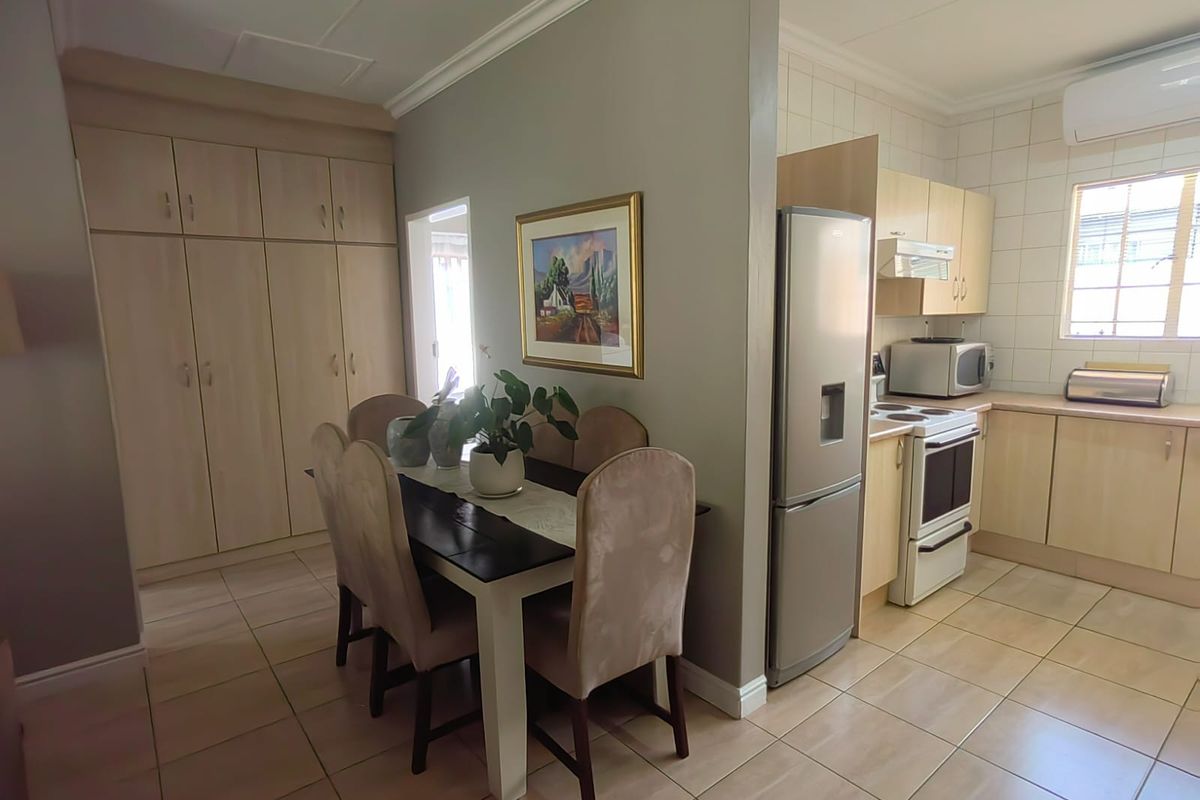 A functional kitchen featuring light wood cabinetry, tiled flooring, and a tiled backsplash, adjacent to a dining area with built-in storage cupboards.