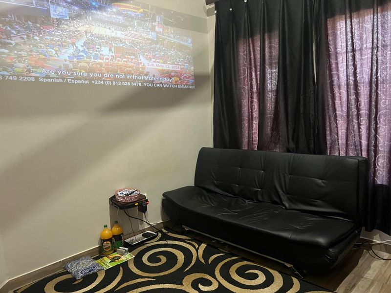 A living room space featuring tiled flooring and window treatments, currently set up with a projector screen display.