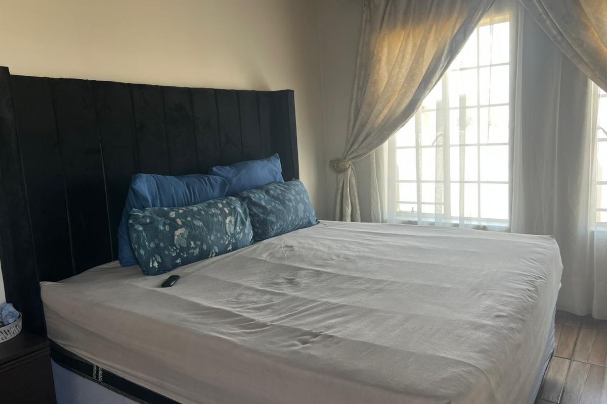 A bedroom featuring tiled flooring and a window with a grid pattern, providing natural light to the space.