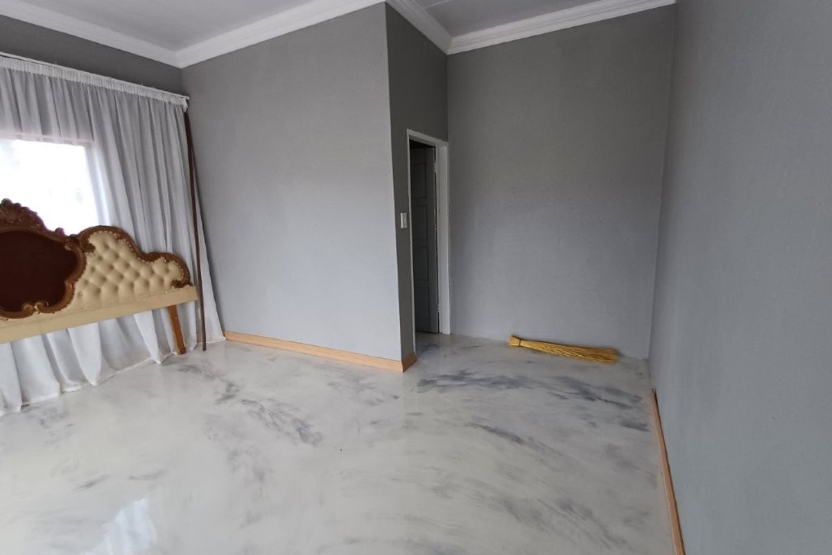 A spacious bedroom featuring modern marbled epoxy resin flooring, crisp grey walls, and decorative crown molding, offering a clean and contemporary blank canvas.