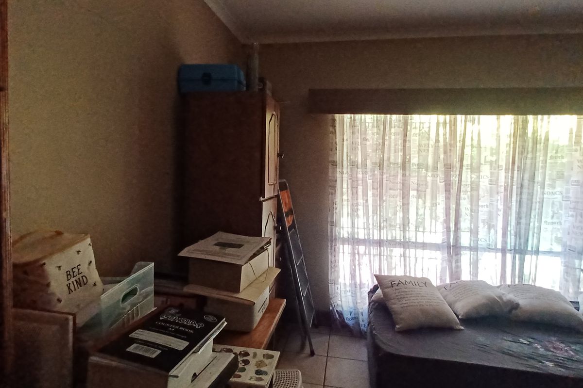 A bedroom featuring tiled flooring and built-in shelving, with a large window providing natural light.