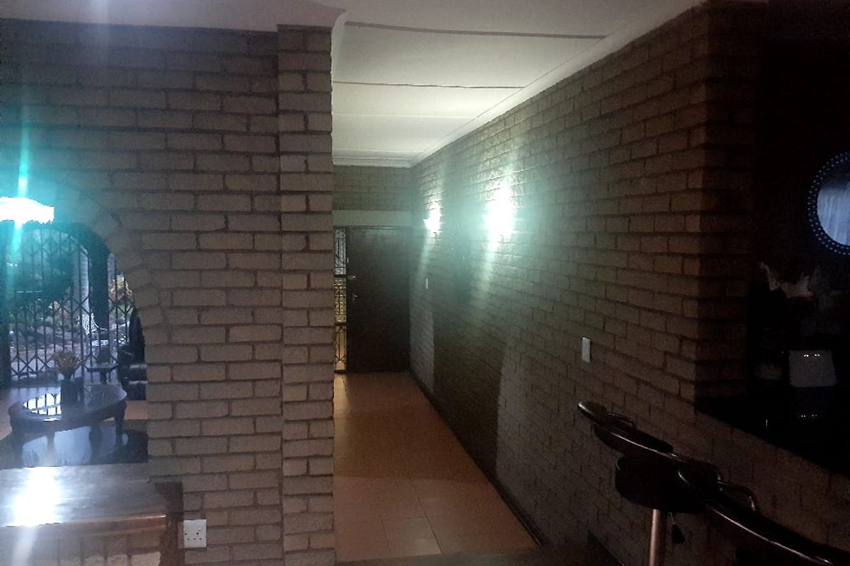 Interior view of a living area featuring exposed brick walls, tiled flooring, and a built-in bar counter with an arched transition to the adjacent space.