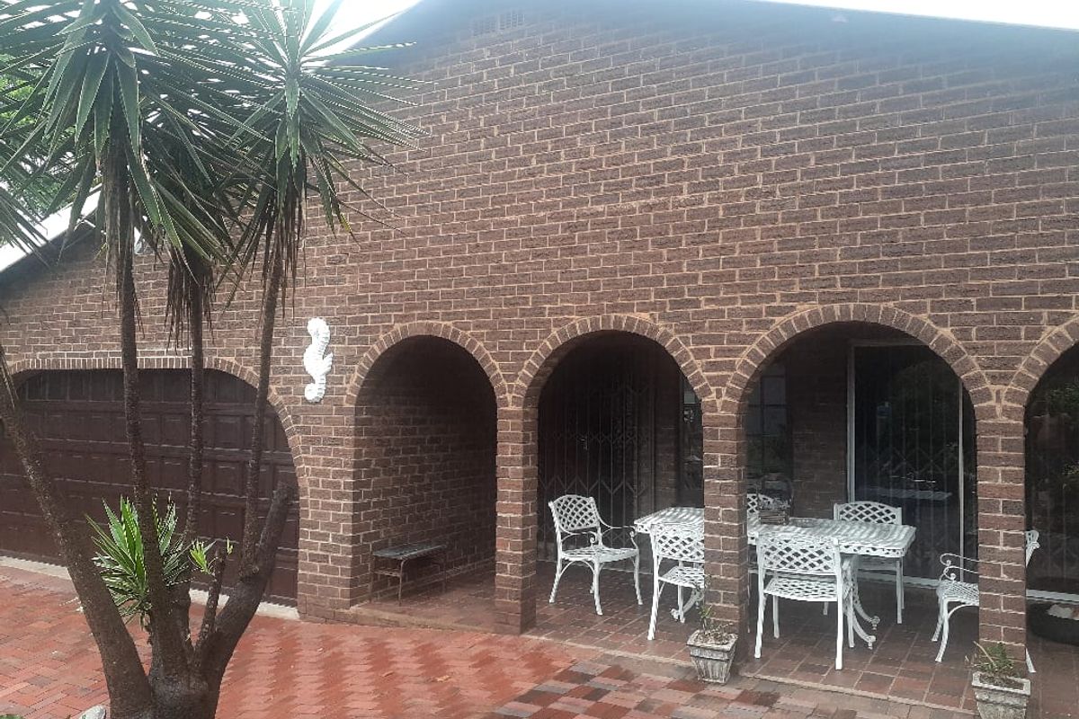 A rear exterior view featuring a brick facade with an arched covered patio area and paved flooring.