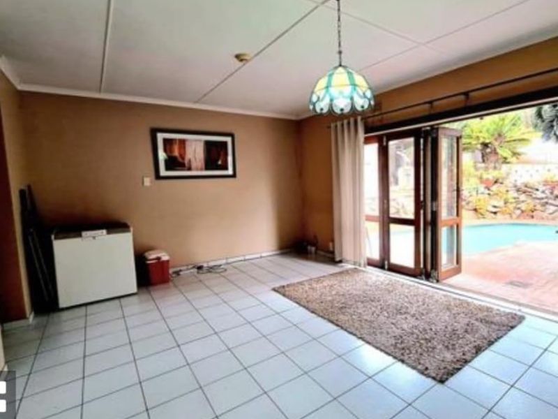 Living room featuring tiled flooring and folding glass doors that open directly onto the pool area.
