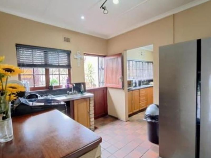 A functional kitchen area featuring tiled flooring, built-in cabinetry, a sink, and a stable door leading to the exterior.