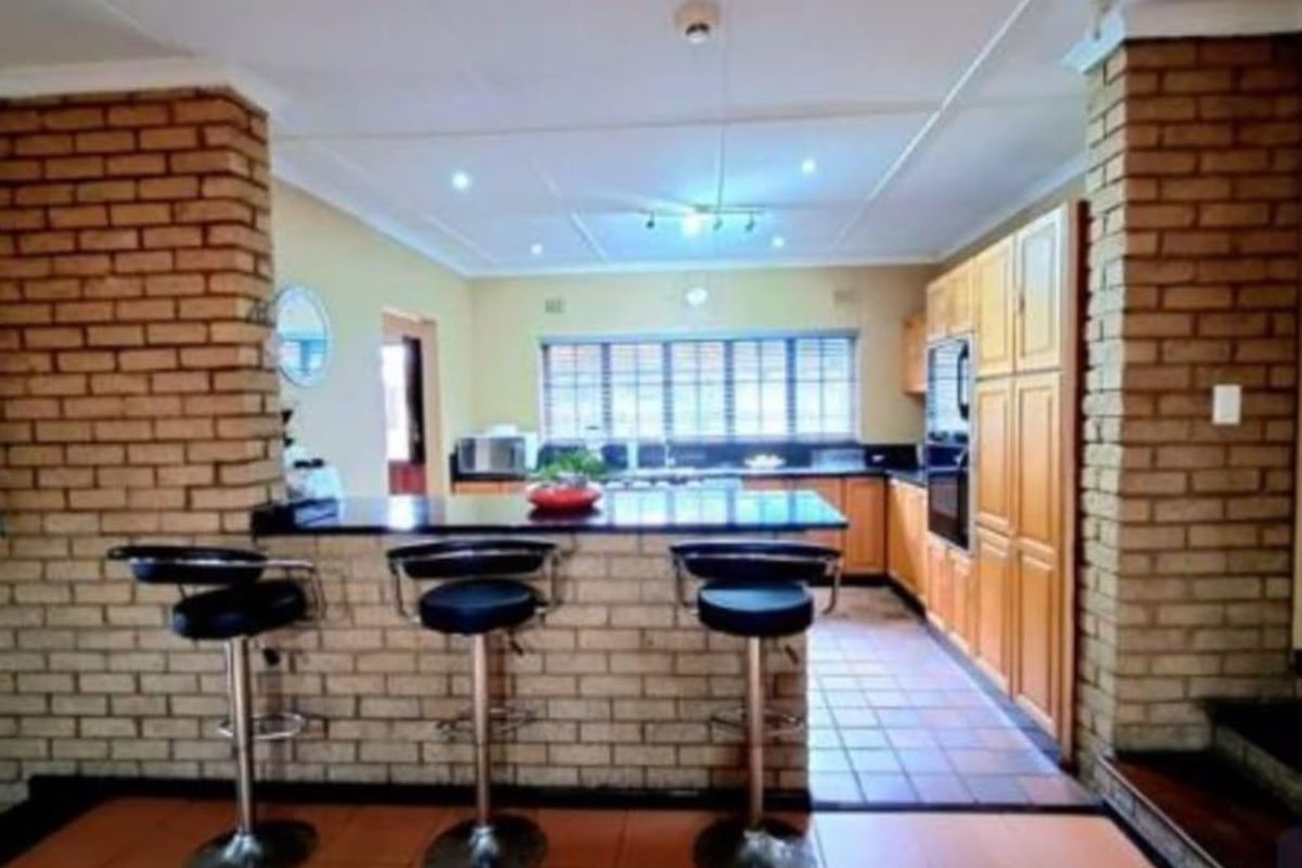 A functional kitchen featuring a brick breakfast bar, built-in oven, fitted cabinetry, and tiled flooring, offering a rustic aesthetic with potential for modernization.