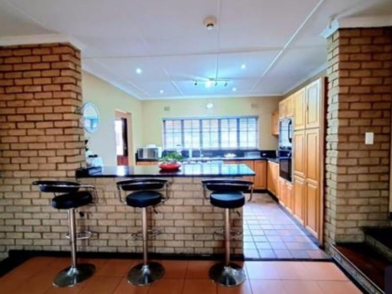 A functional kitchen featuring a brick breakfast bar, built-in oven, fitted cabinetry, and tiled flooring, offering a rustic aesthetic with potential for modernization.