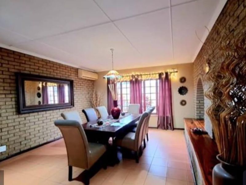 A dining room featuring exposed brick walls, tiled flooring, and an arched architectural detail, providing a warm and textured space for family meals.