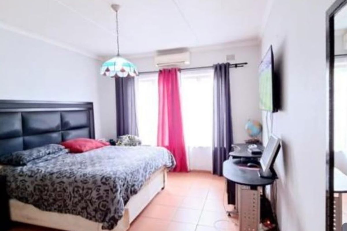 A bedroom featuring tiled flooring, coved ceilings, and a wall-mounted air conditioning unit.