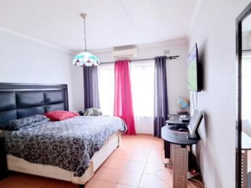 A bedroom featuring tiled flooring, coved ceilings, and a wall-mounted air conditioning unit.