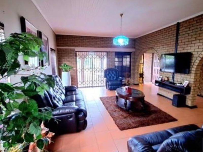 Spacious living room featuring exposed brick walls, tiled flooring, and an arched entryway leading to adjacent areas.