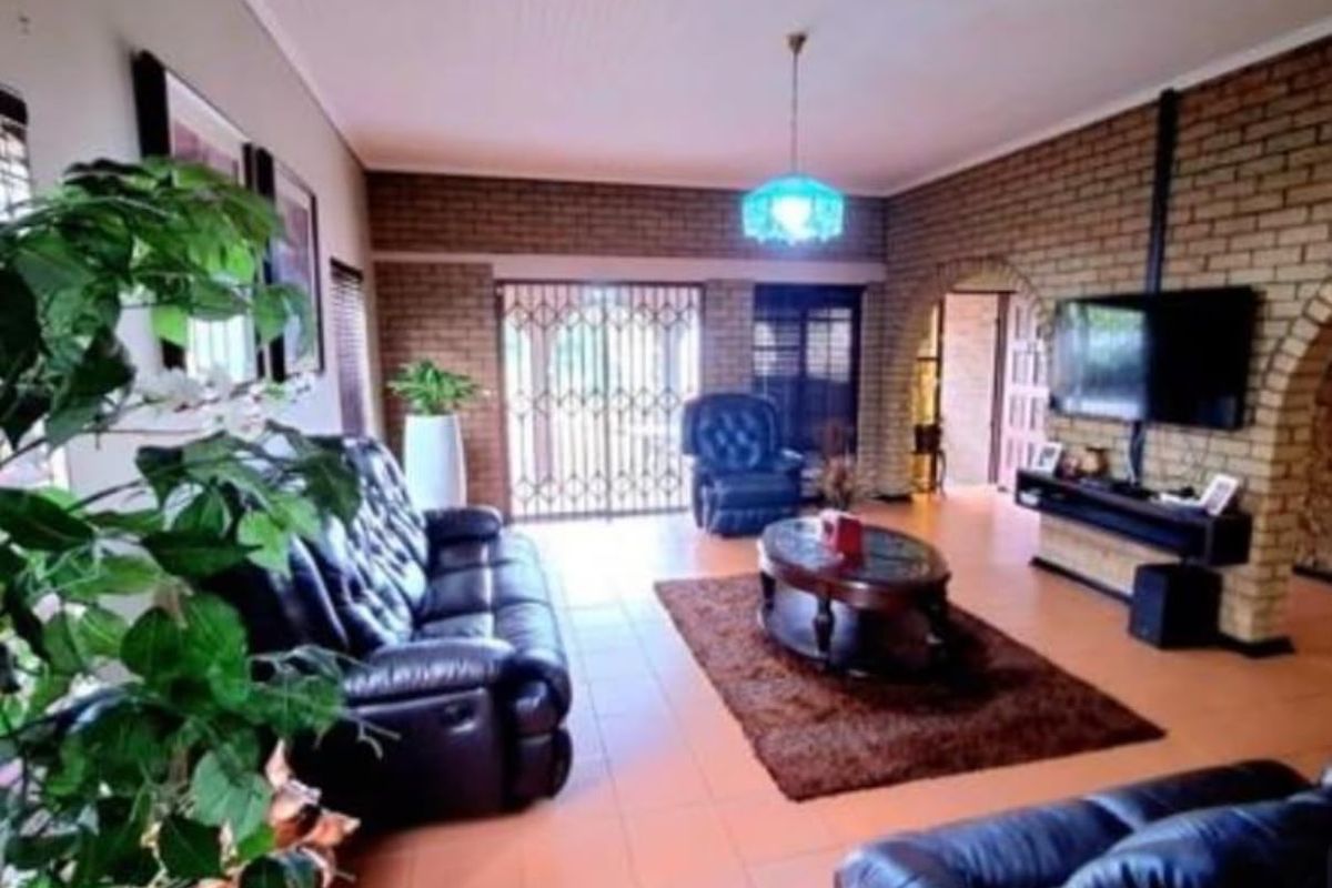 Spacious living room featuring exposed brick walls, tiled flooring, and an arched entryway leading to adjacent areas.