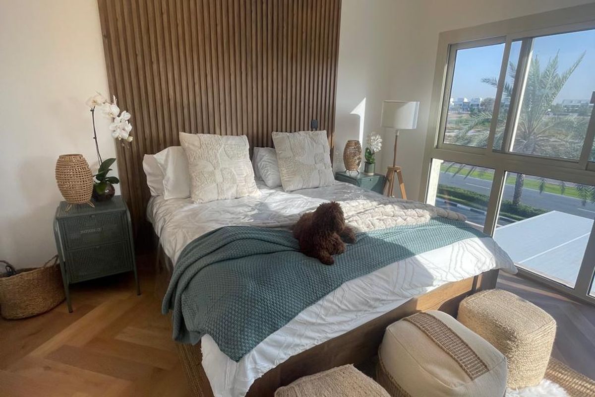 A well-appointed bedroom featuring a timber slat feature wall, herringbone wood flooring, recessed ceiling lighting, and large sliding glass doors with exterior views.