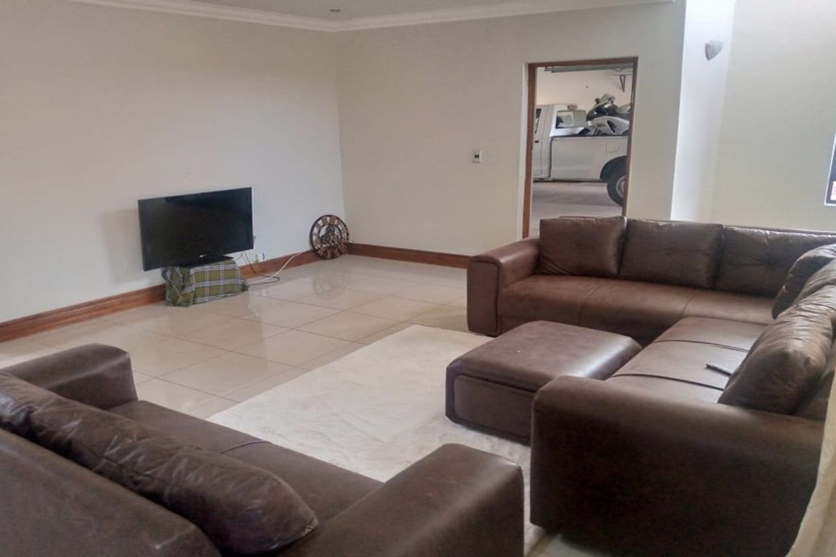 A spacious living room featuring neutral tiled flooring, clean wall finishes, and recessed lighting, providing a versatile area for relaxation.