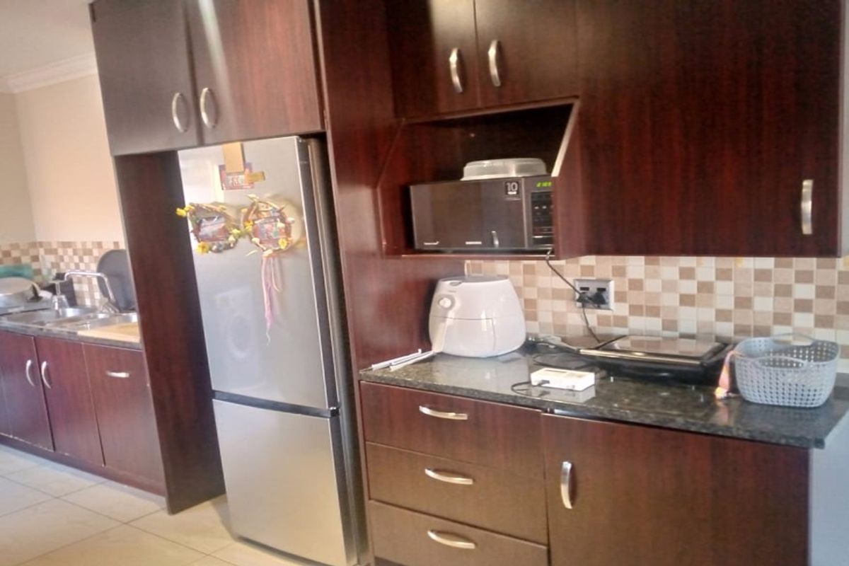 A functional kitchen featuring dark wood cabinetry, granite countertops, a tiled backsplash, and built-in microwave space.