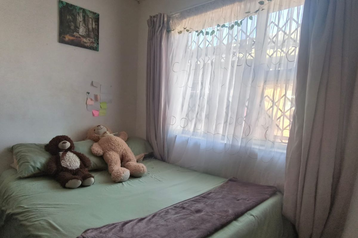 A bedroom featuring a window with a security gate and a tiled ceiling.