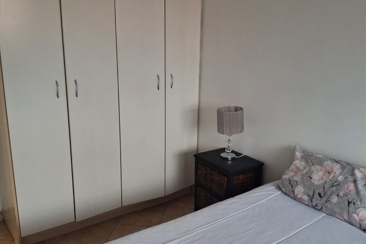 A bedroom featuring built-in floor-to-ceiling wardrobes and tiled flooring.