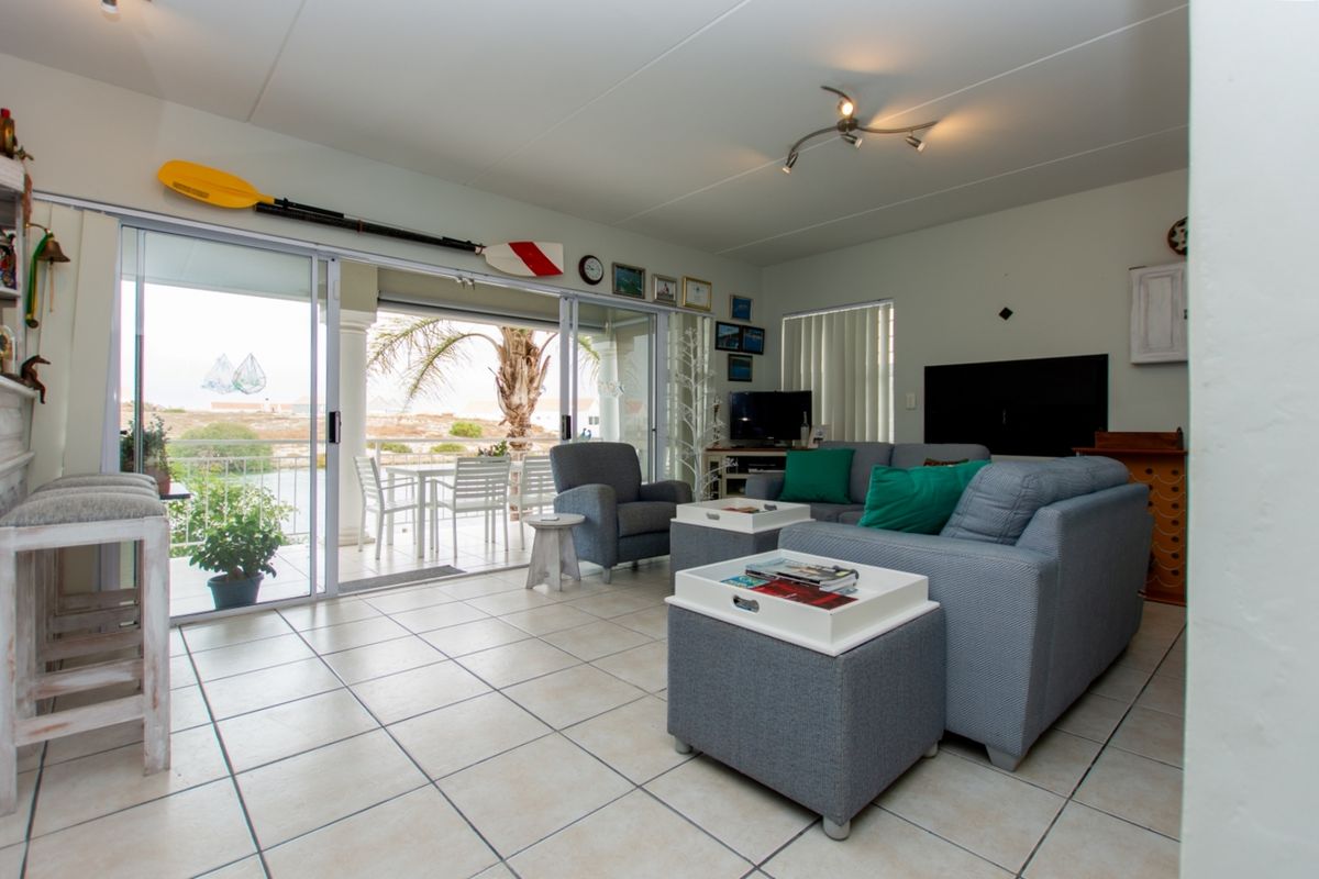 Spacious living room featuring neutral tiled flooring and large sliding glass doors that provide seamless access to the covered outdoor patio area.