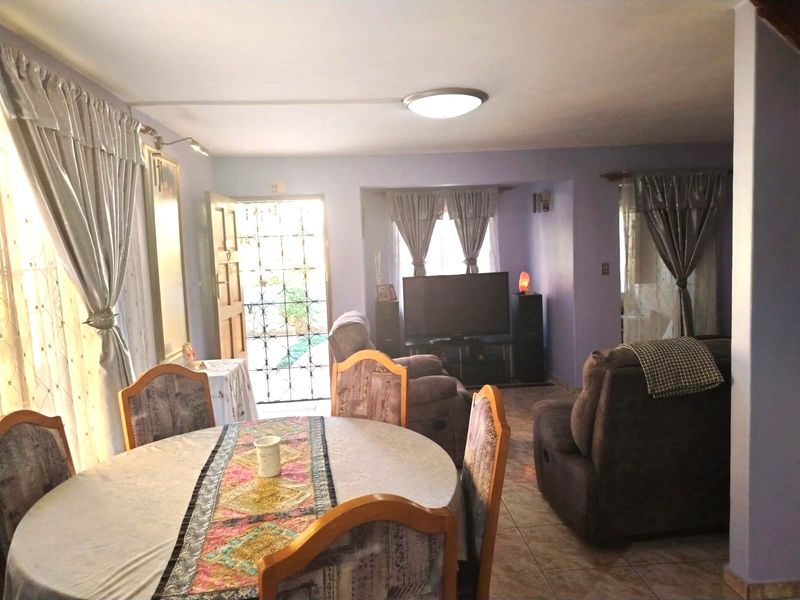 Open plan living and dining area featuring tiled flooring and direct access to the exterior through a security gate.