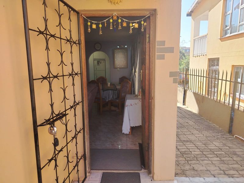 View through the entrance door into an open plan living and dining area, featuring tiled flooring and a security gate.