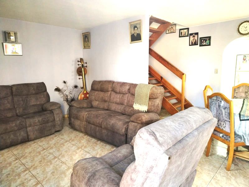 Open plan living and dining area featuring tiled flooring and a wooden staircase leading to the upper level.