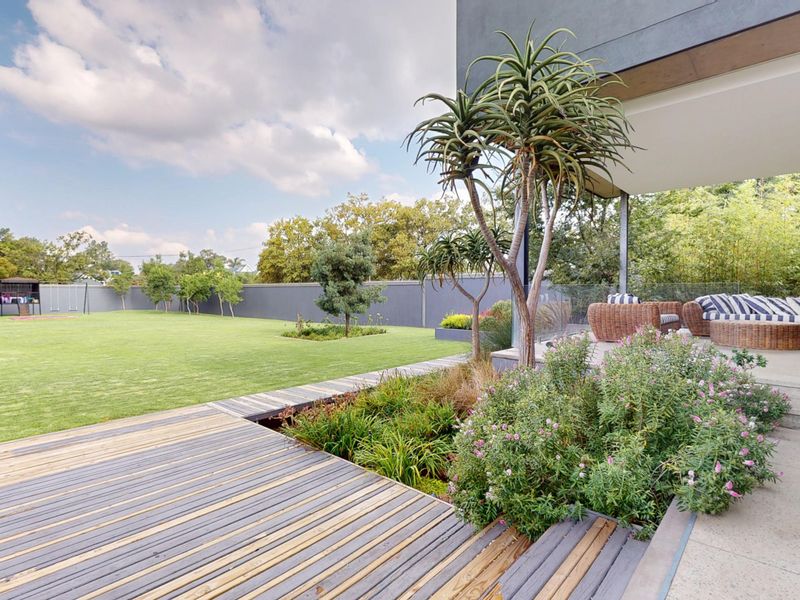 Spacious rear garden featuring a timber deck, concrete patio area, and well-maintained lawn, perfect for outdoor entertaining.