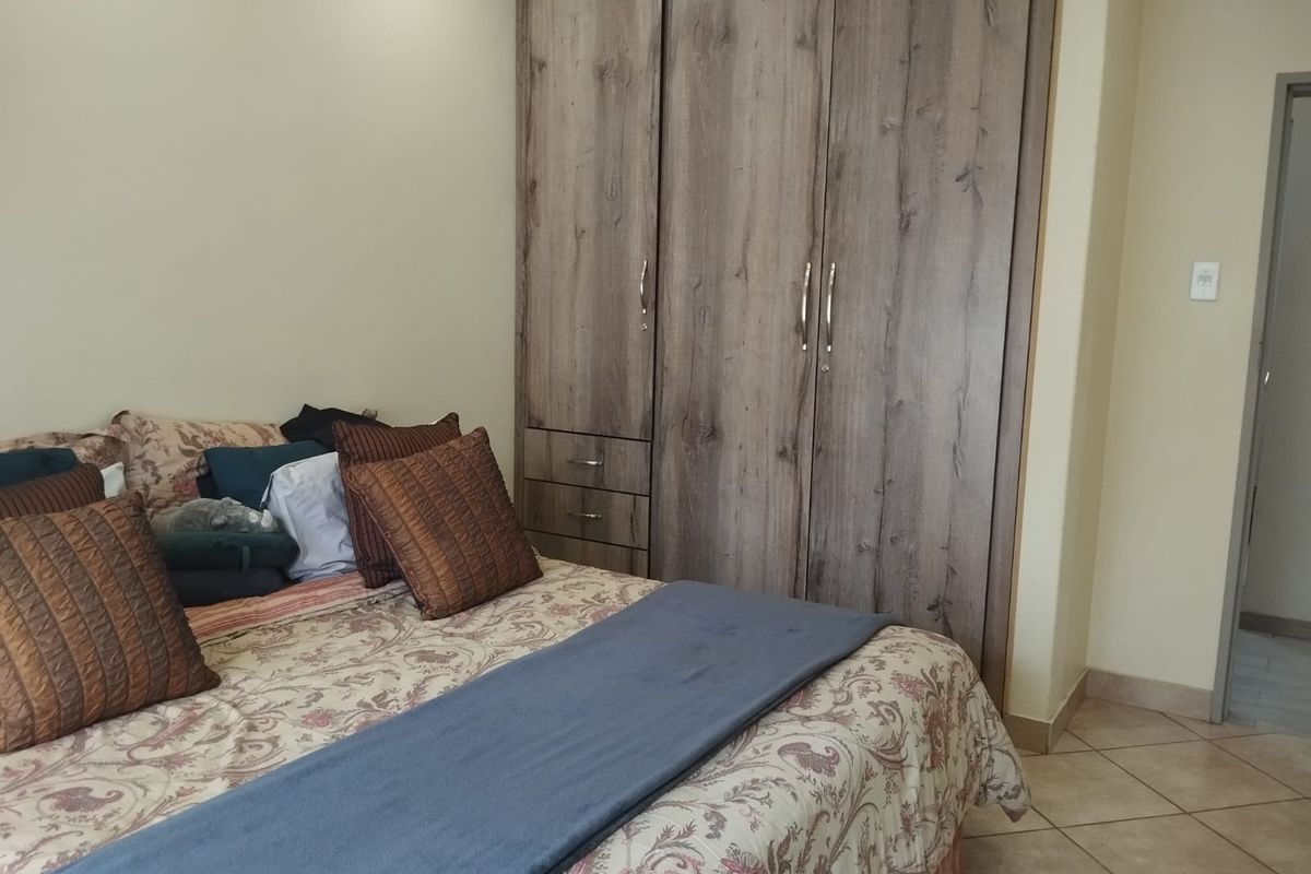 A bedroom featuring a large built-in wooden wardrobe and tiled flooring.