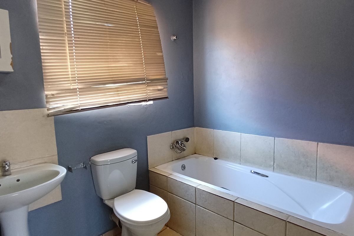 A functional bathroom featuring a pedestal basin, toilet, and a built-in bathtub with tiled surround and flooring.
