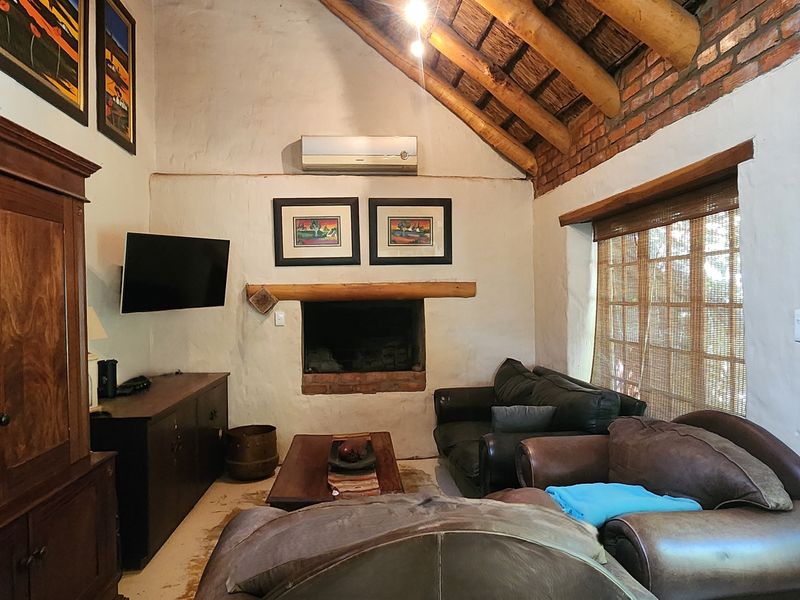 Cozy living room featuring a high vaulted ceiling with exposed timber rafters, thatched roof detail, exposed brick accents, and a built-in fireplace.