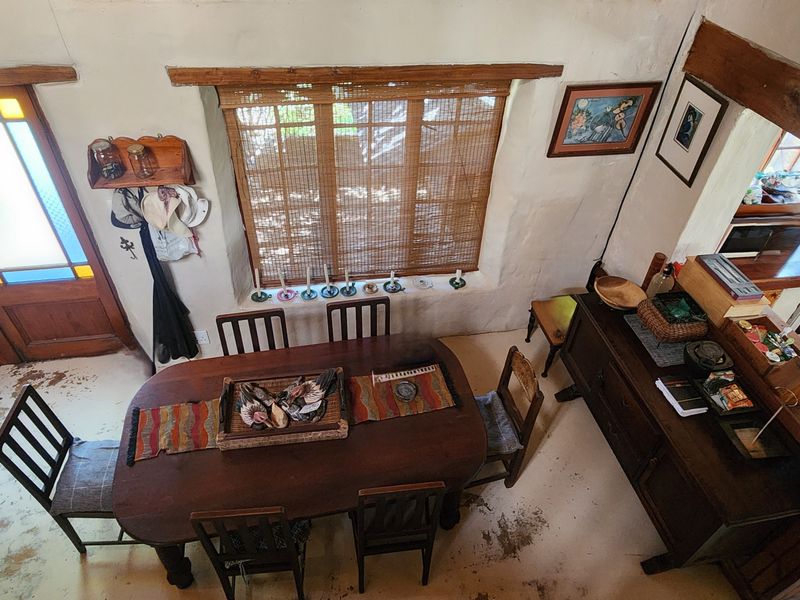Open plan living and dining area featuring exposed timber beams, rustic finishes, and an adjoining kitchen with built-in cabinetry and appliances.