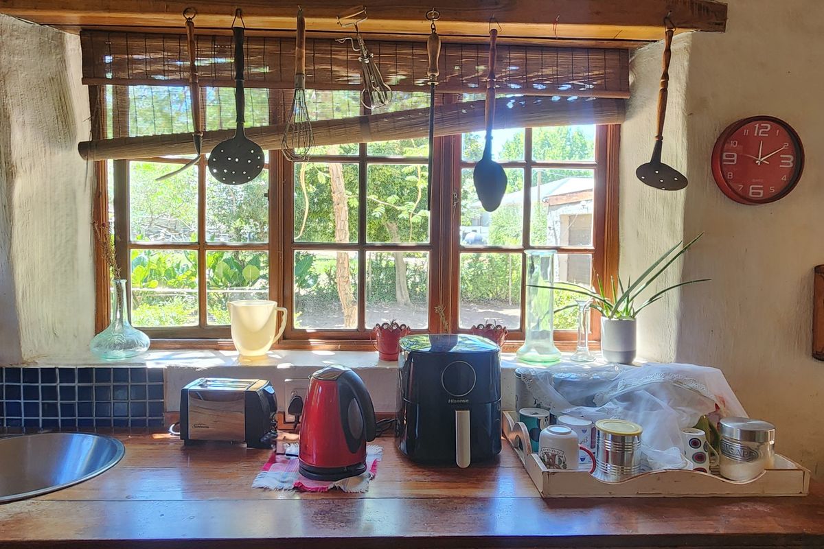 Rustic kitchen area featuring a timber countertop, stainless steel sink, and a large window with natural light, showcasing a charming, lived-in aesthetic.