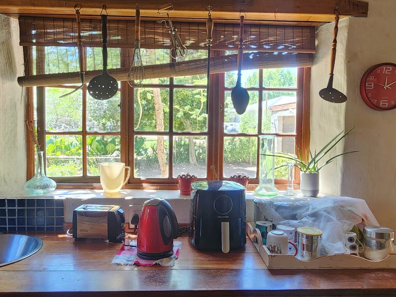 Rustic kitchen area featuring a timber countertop, stainless steel sink, and a large window with natural light, showcasing a charming, lived-in aesthetic.