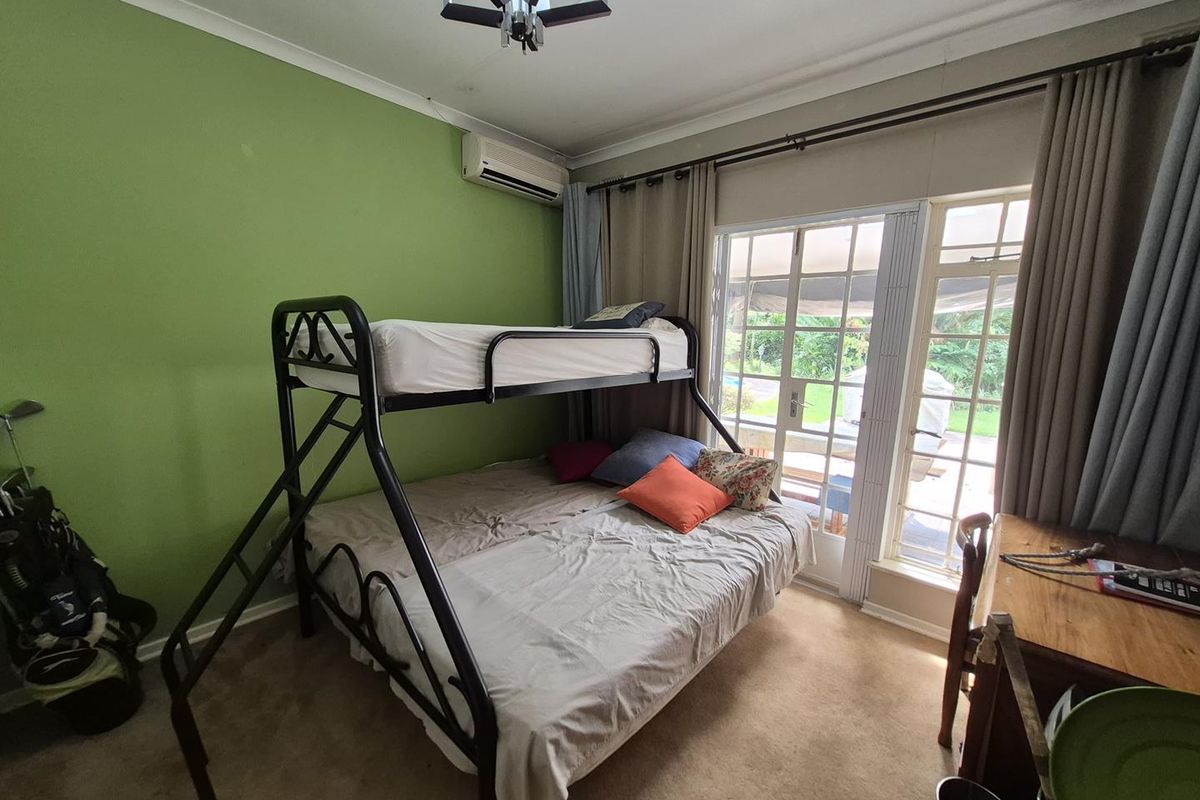 Bedroom featuring carpeted flooring, wall-mounted air conditioning unit, and glass sliding doors providing direct access to the outdoor patio area.