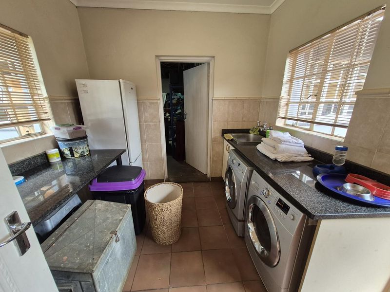 Functional laundry room featuring granite countertops, tiled flooring, and dedicated space for laundry appliances with natural light from dual windows.