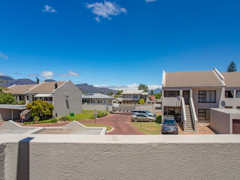 Elevated view overlooking the residential complex, paved driveway, and surrounding mountain landscape.