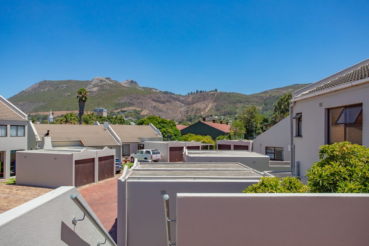 An elevated view of the apartment complex exterior, featuring paved driveways, garage units, and scenic mountain views in the background.