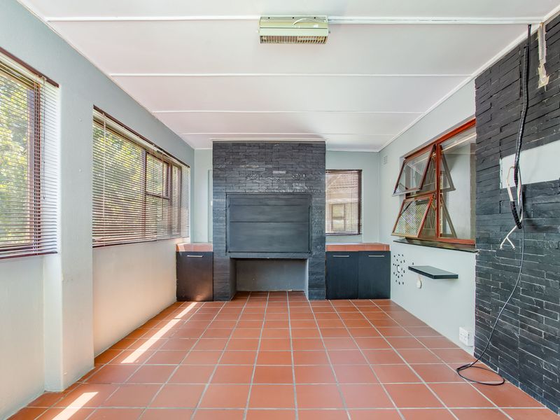 Enclosed patio area featuring a built-in braai, tiled flooring, and stone-clad feature walls, offering a versatile space for outdoor entertaining.