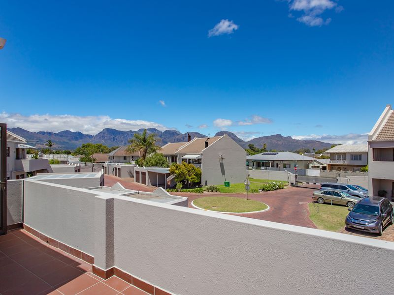 Elevated view from a tiled balcony overlooking the residential complex grounds and surrounding mountain range.
