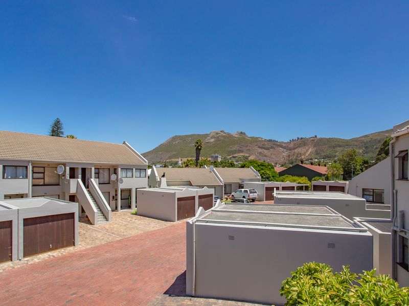 An elevated view of an apartment complex featuring paved driveways, multiple garage units, and a mountain backdrop.